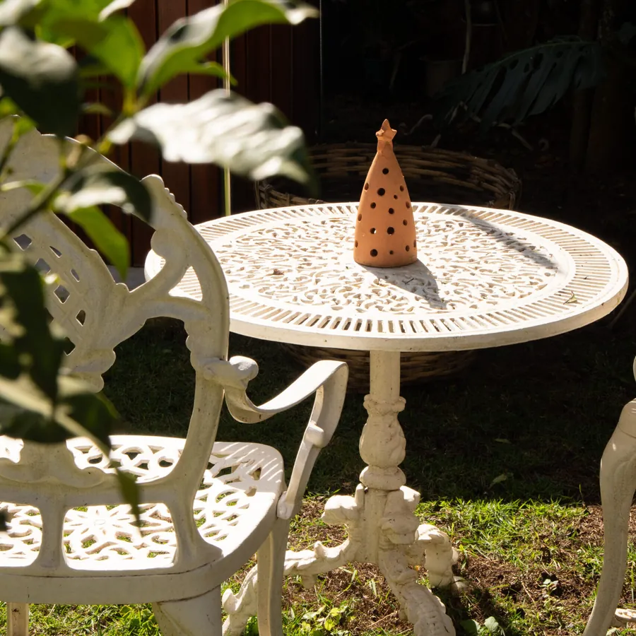 Mesa e cadeira de ferro fundido brancas no jardim da pousada